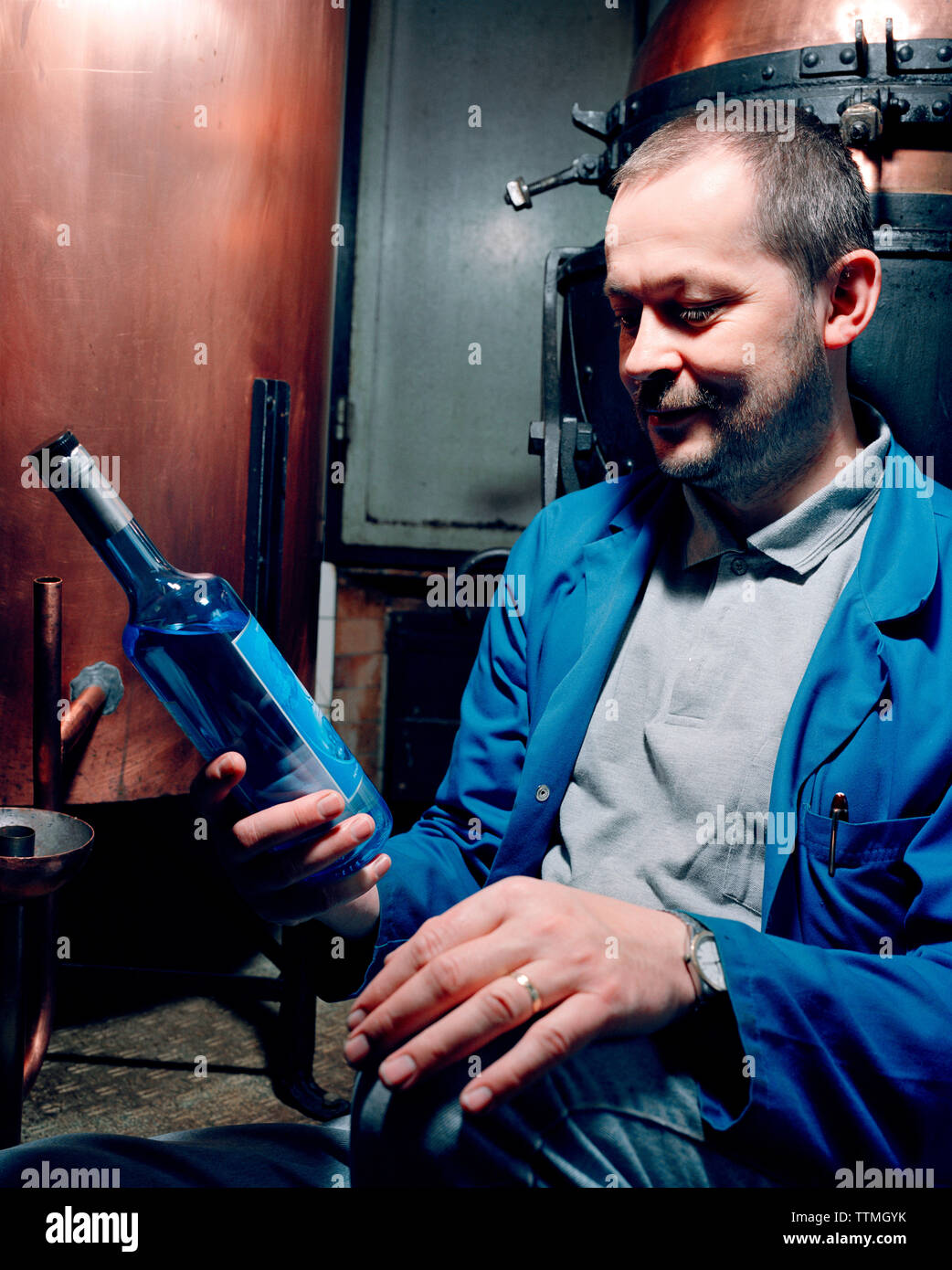 SWITZERLAND, Couvet, Absinthe maker Claude-Alain Bugnon holding a bottle at his Artemisia Distillerie, Jura Region Stock Photo
