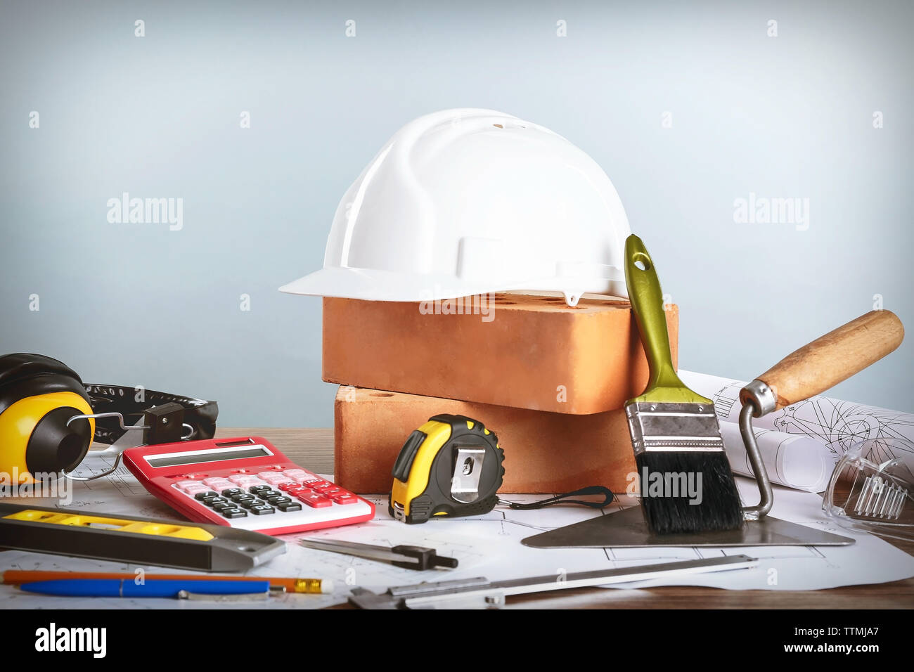 Construction blueprints with tools and helmet on light background Stock Photo