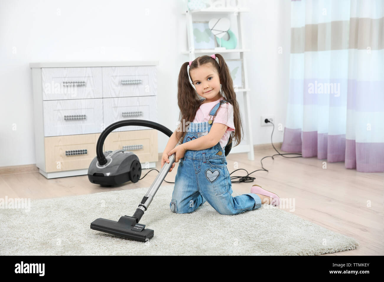 Cute little girl using vacuum cleaner in room Stock Photo Alamy