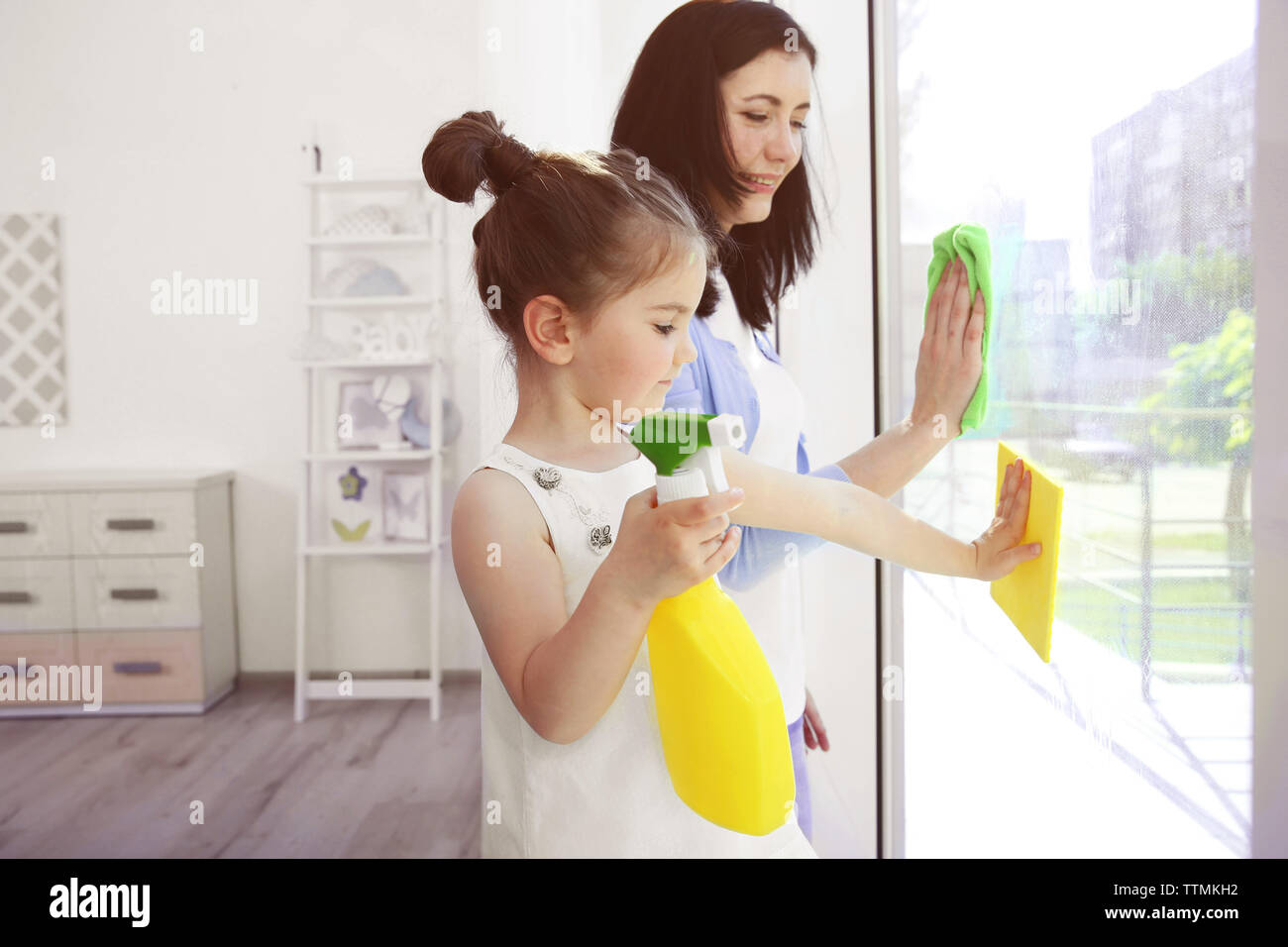 Daughter and mother cleaning window together Stock Photo - Alamy