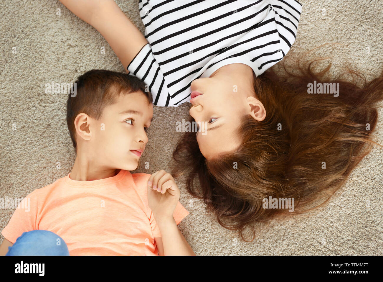 Brother and sister lying on carpet Stock Photo