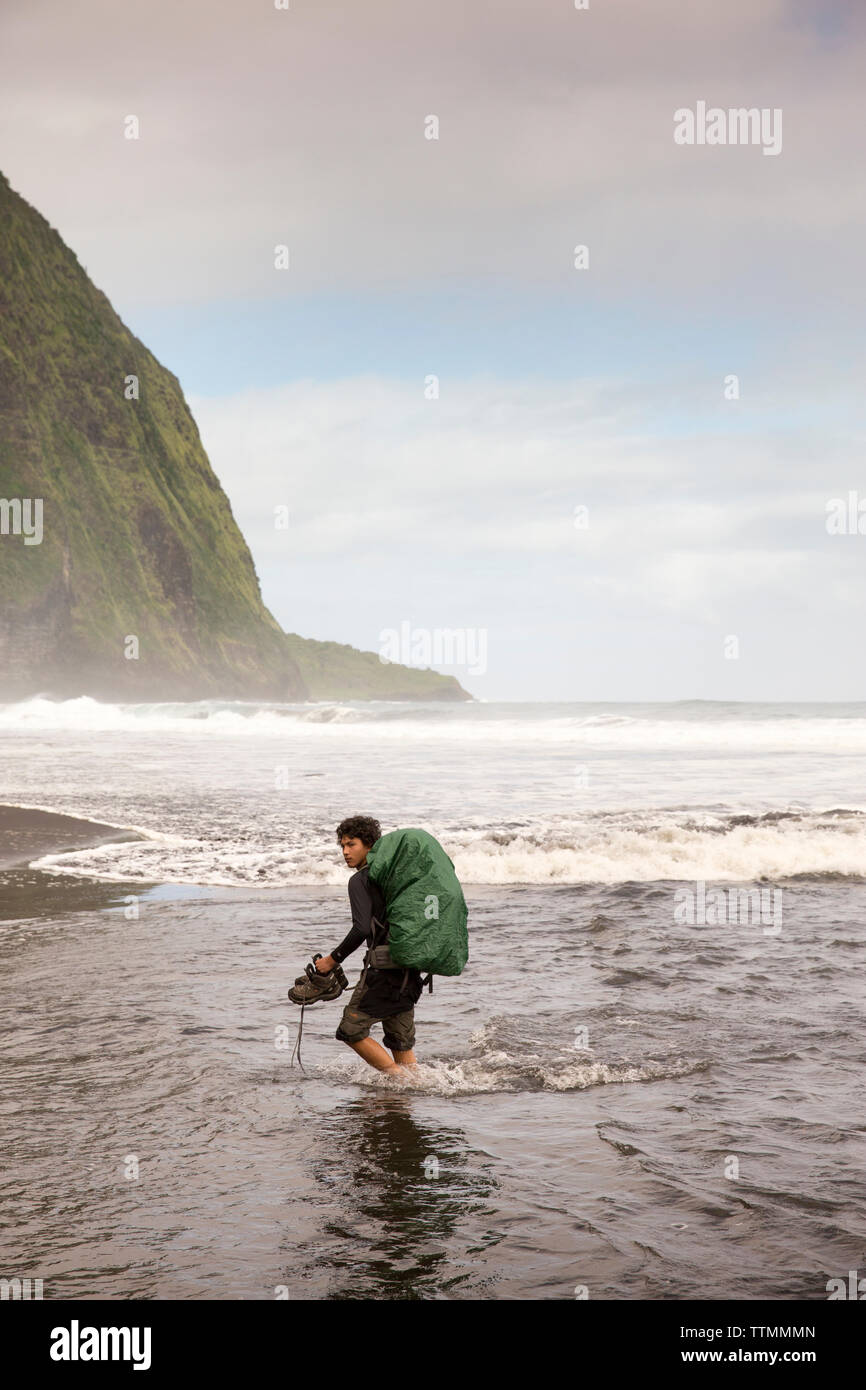 USA, Hawaii, The Big Island, backpacker walks on the beach along the