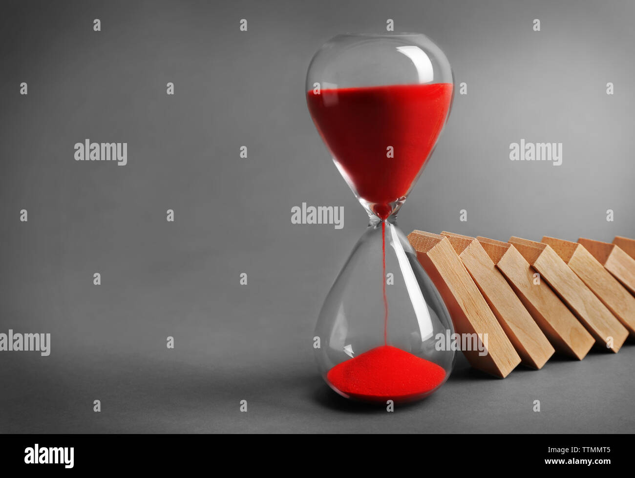 Hour glass blocked row of falling dominoes on grey background Stock ...