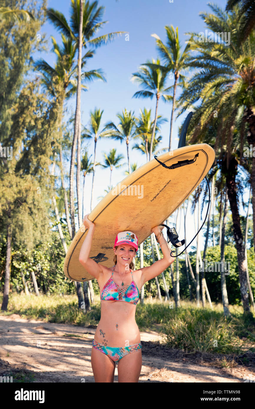 HAWAII, Oahu, North Shore, young woman heading out for a surf at Puaena Point Beach Park Stock Photo