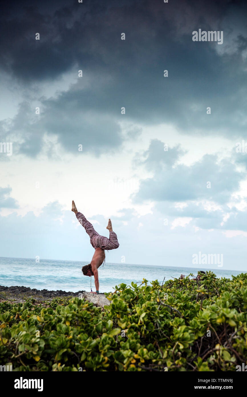 HAWAII, Oahu, North Shore, individual doing yoga on the rocks near the