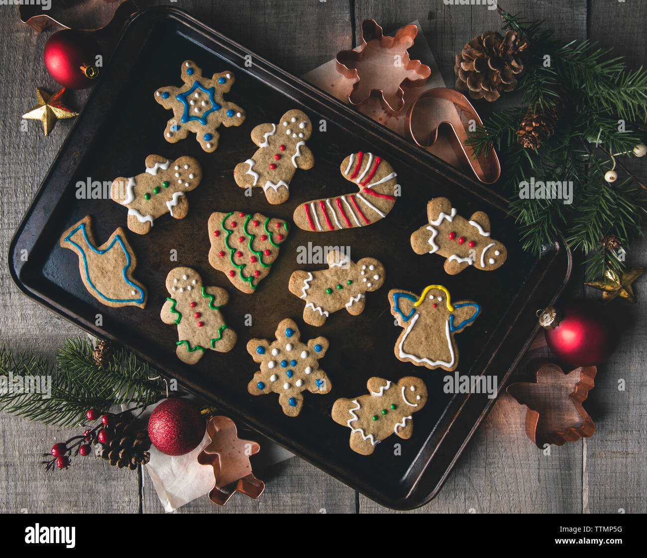 Overhead view of gingerbread cookies in baking sheet by pastry cutters on table Stock Photo