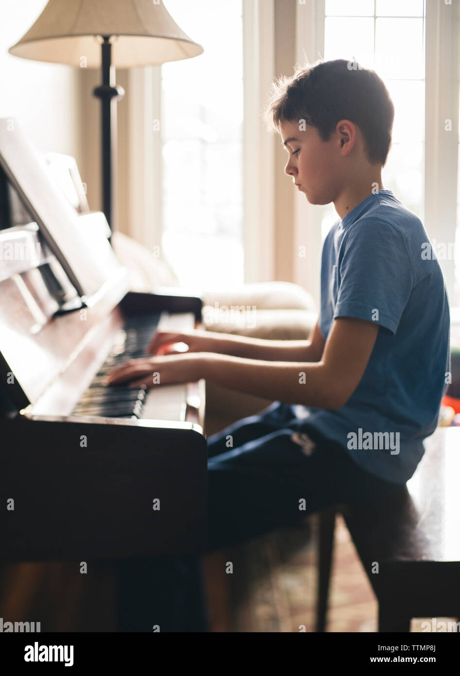 Side view of boy playing piano while sitting at home Stock Photo - Alamy