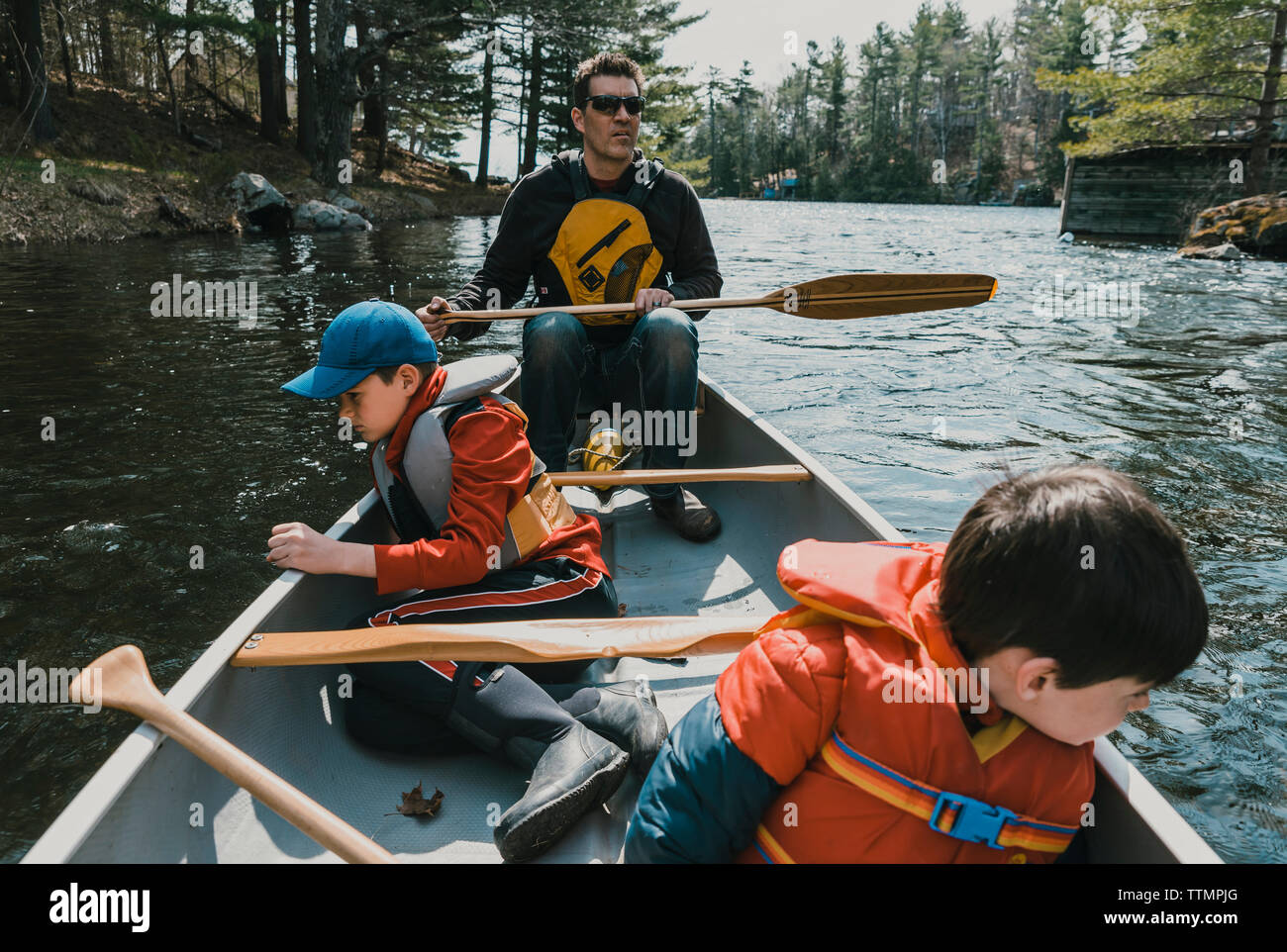 Father and sons canoeing on lake in forest Stock Photo