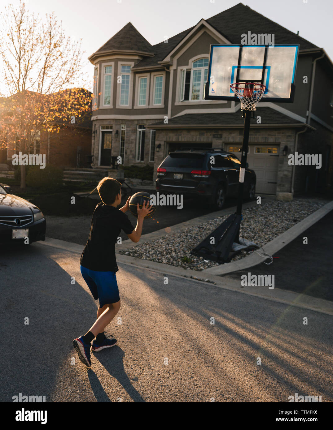 Full length of boy playing basketball on road by house Stock Photo