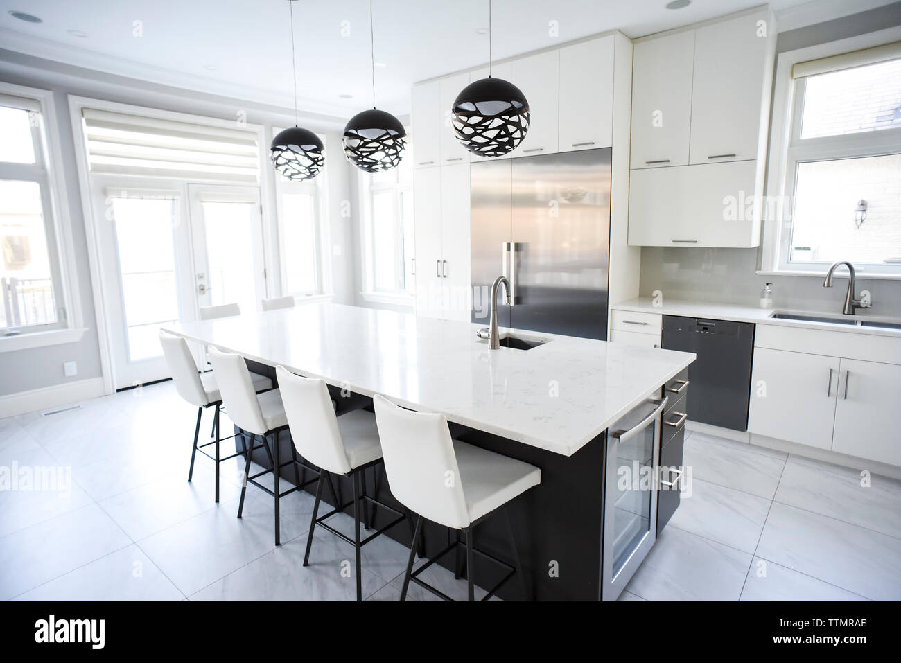 Modern white kitchen with large island and stainless steel appliances. Stock Photo