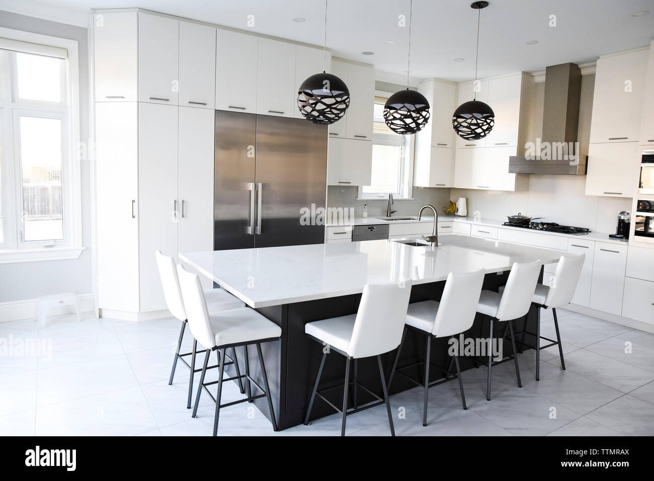 A modern farmhouse kitchen with white cabinets, a wood island with chairs,  Viking stainless steel appliances, and a dark granite countertop Stock  Photo - Alamy