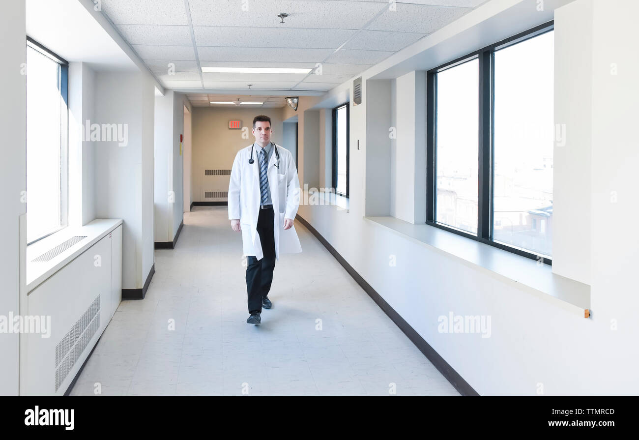 Doctor in a white coat walking down a hallway in a hospital. Stock Photo