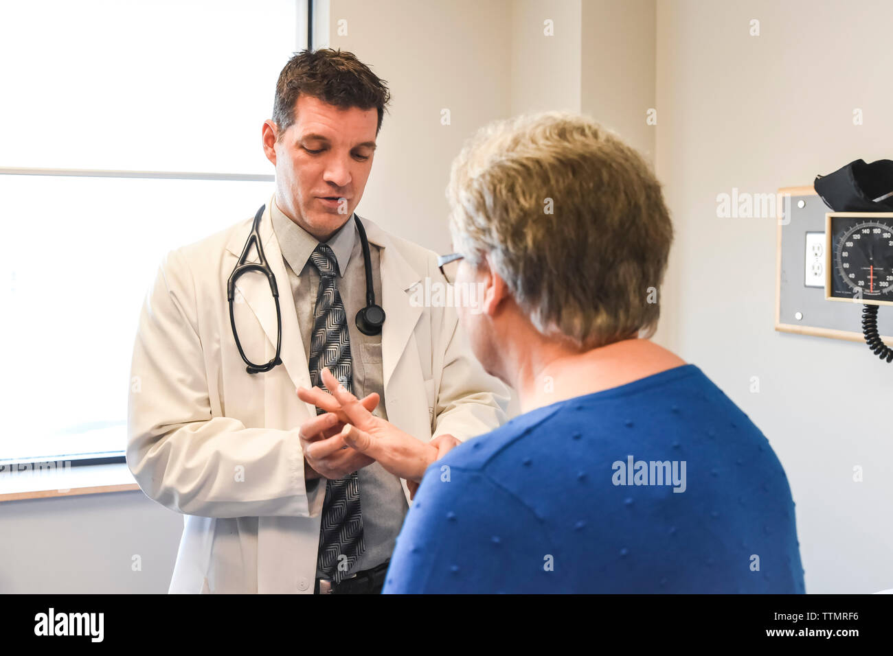 Doctor examining the hand of  an older patient in a clinical setting. Stock Photo