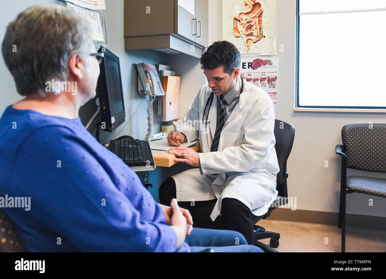 Doctor taking patient history from older woman at a desk in a clinic