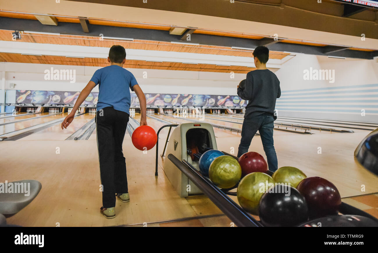 Two boys holding bowling balls at a bowling alley together. Stock Photo