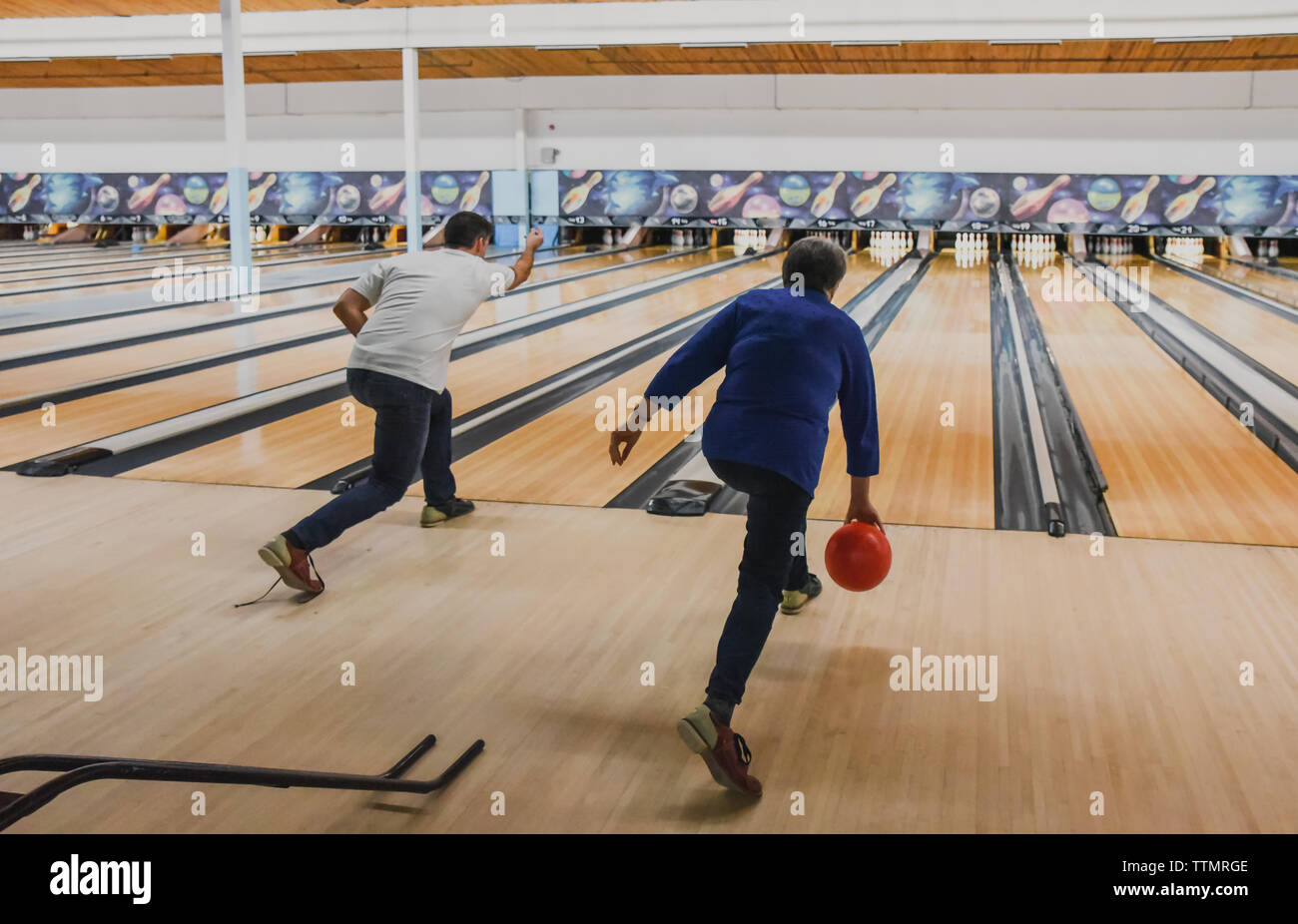 Man and older woman and  throwing bowling balls at same time.. Stock Photo