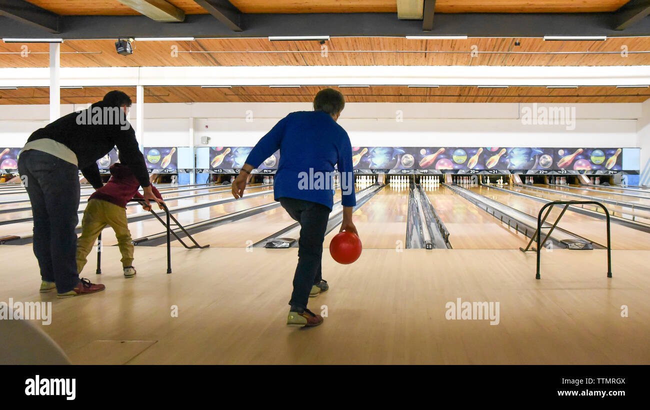 Older woman and father with child bowling together at bowling alley. Stock Photo