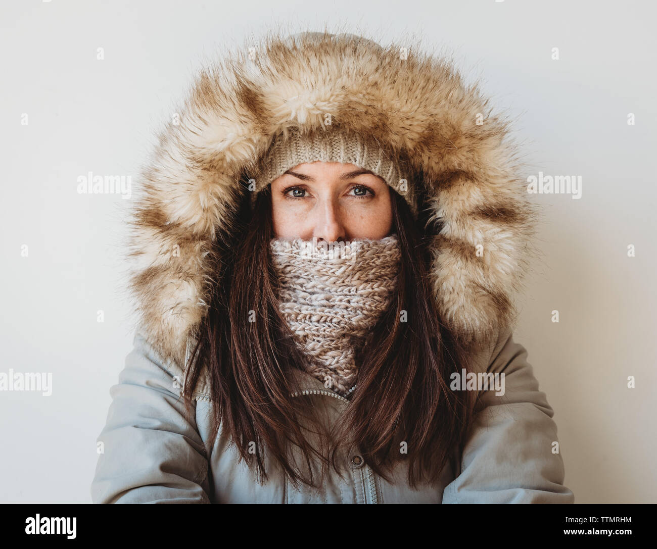 Portrait of woman in winter clothing against white background. Stock Photo