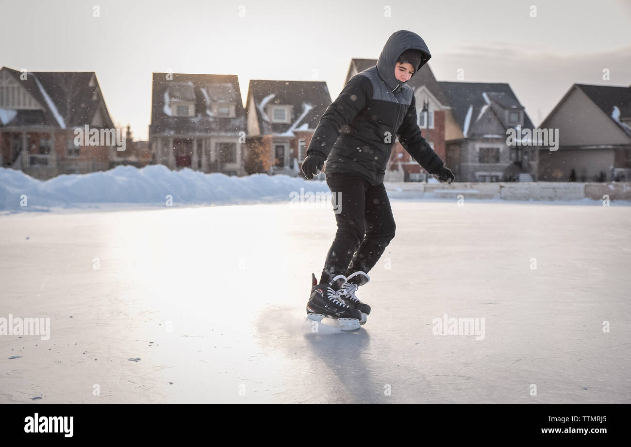 Teenage boy skating alone on an outdoor neighbourhood ice rink Stock