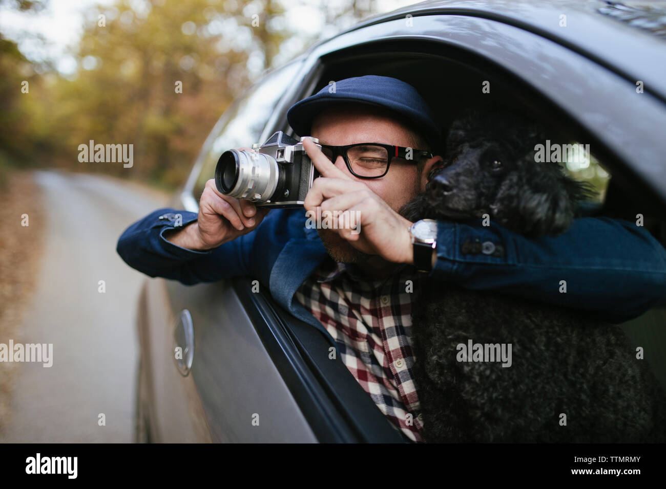 Man photographing while sitting with dog in car Stock Photo