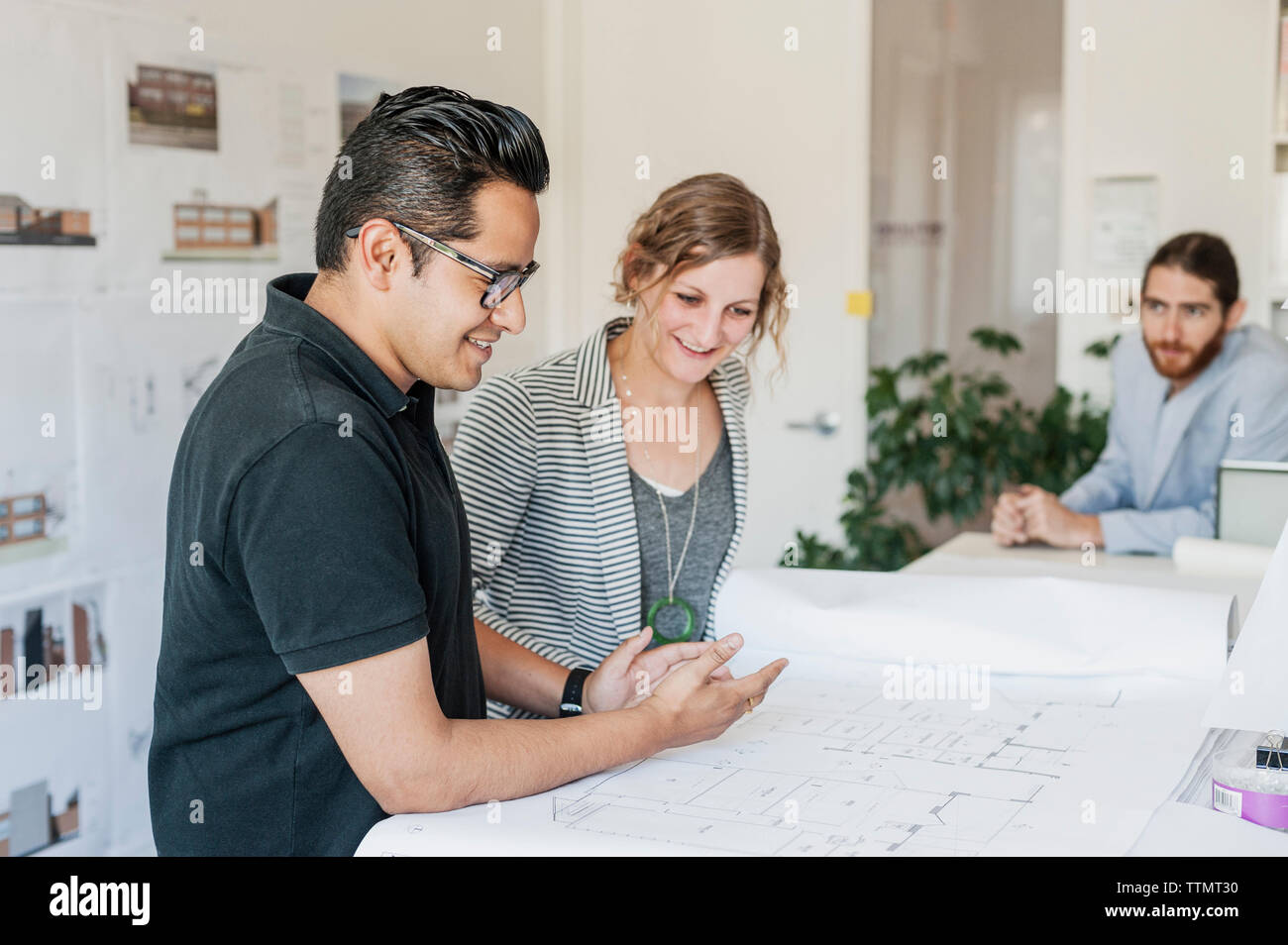 Happy colleagues analyzing blueprints at office Stock Photo