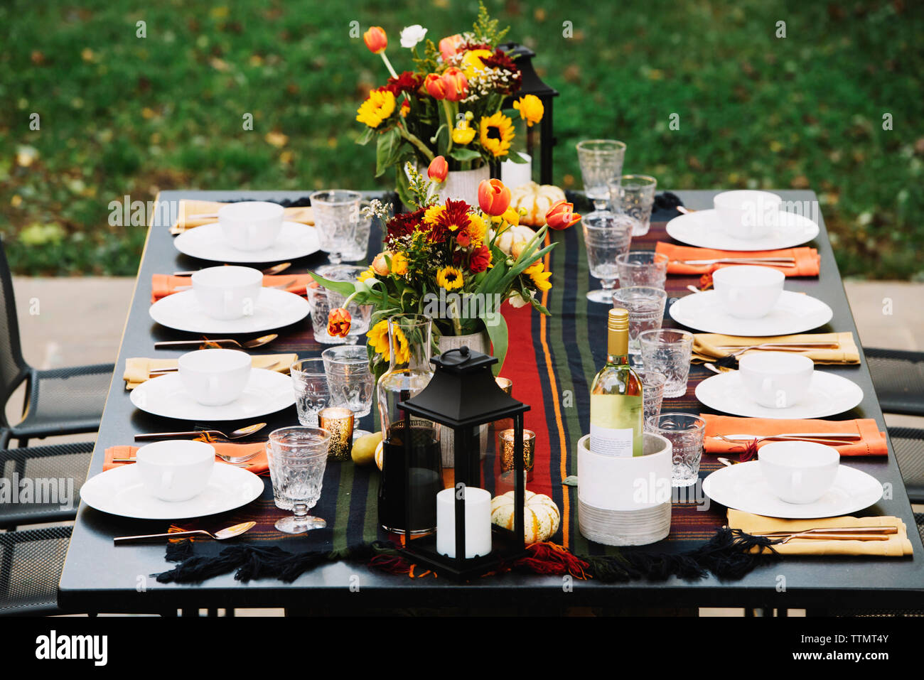 Flower Vases With Crockery Arranged On Dining Table In Backyard