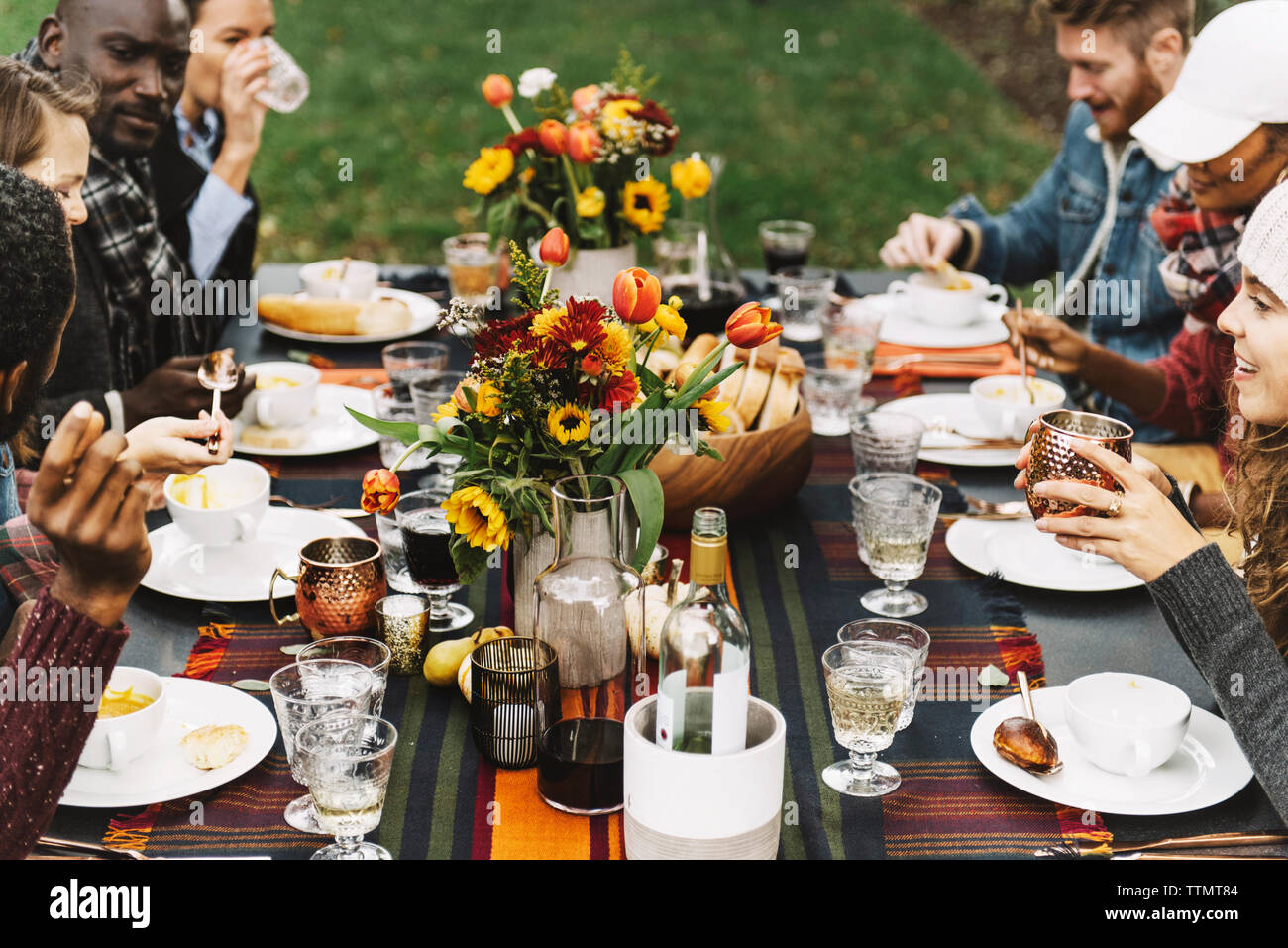 Friends eating food while sitting at table in backyard Stock Photo