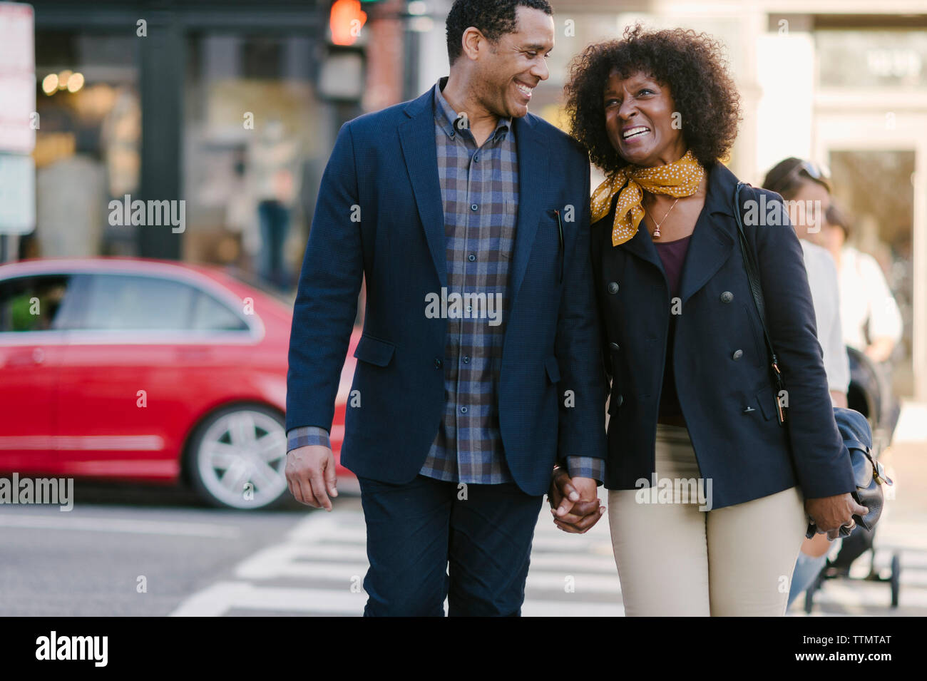 Happy couple holding hands while walking on city street Stock Photo - Alamy