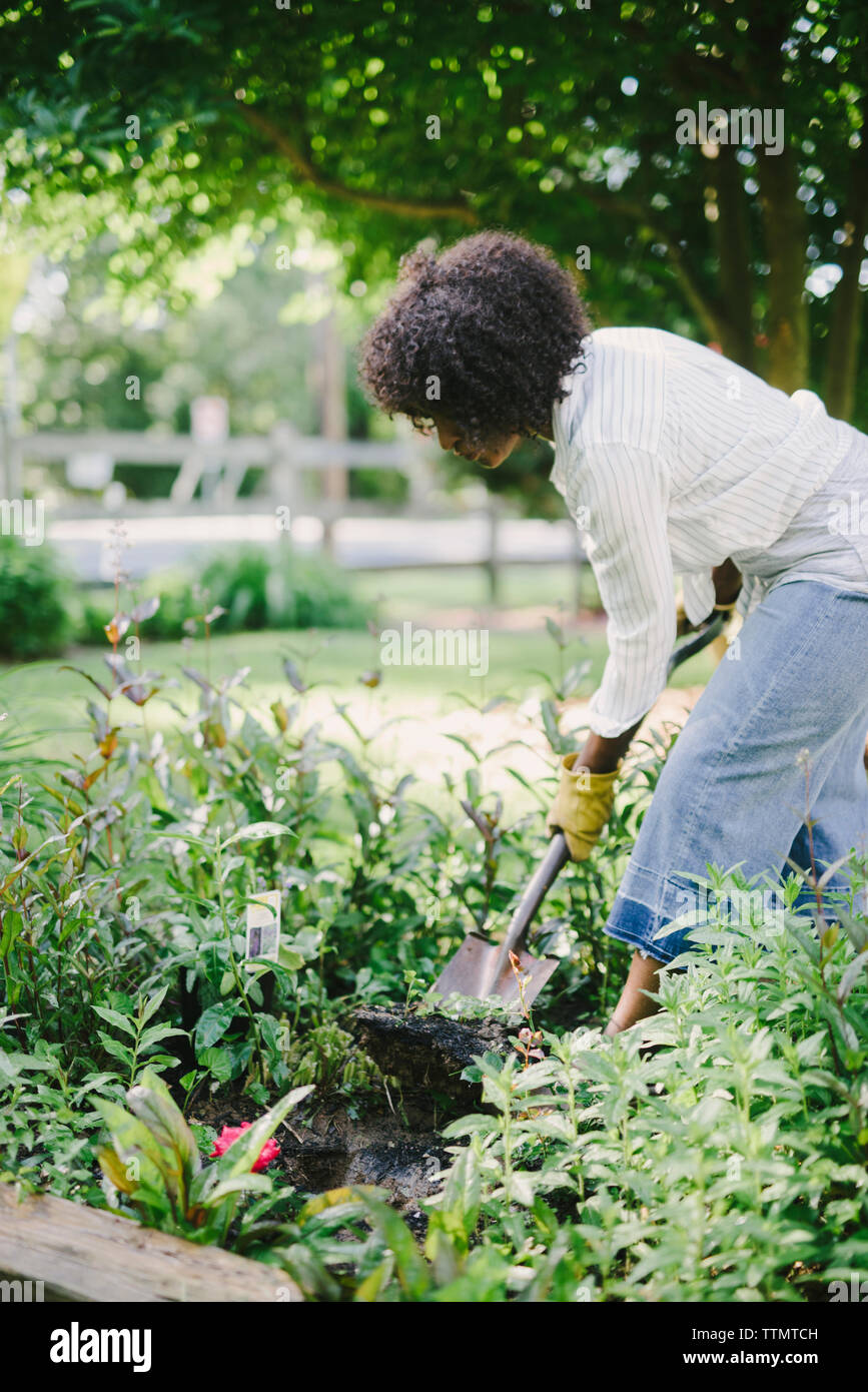 Woman digging soil with shovel in garden Stock Photo