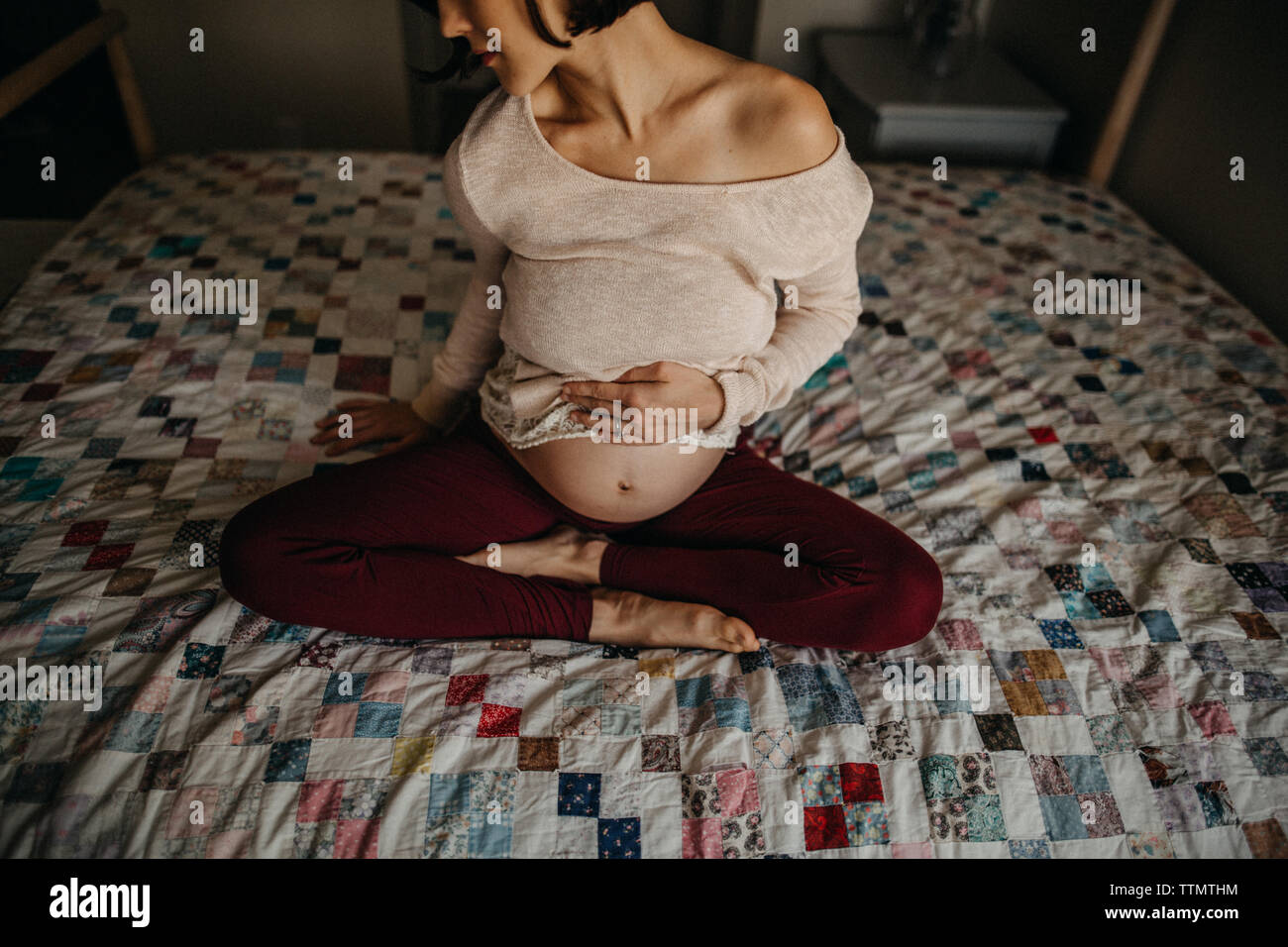 Young pregnant woman sitting in bed holding her baby bump Stock Photo
