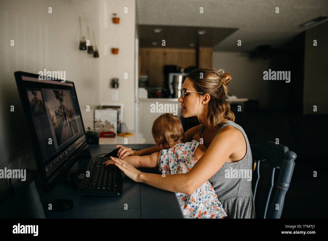 Multitasking working mother holding baby and typing on computer Stock Photo
