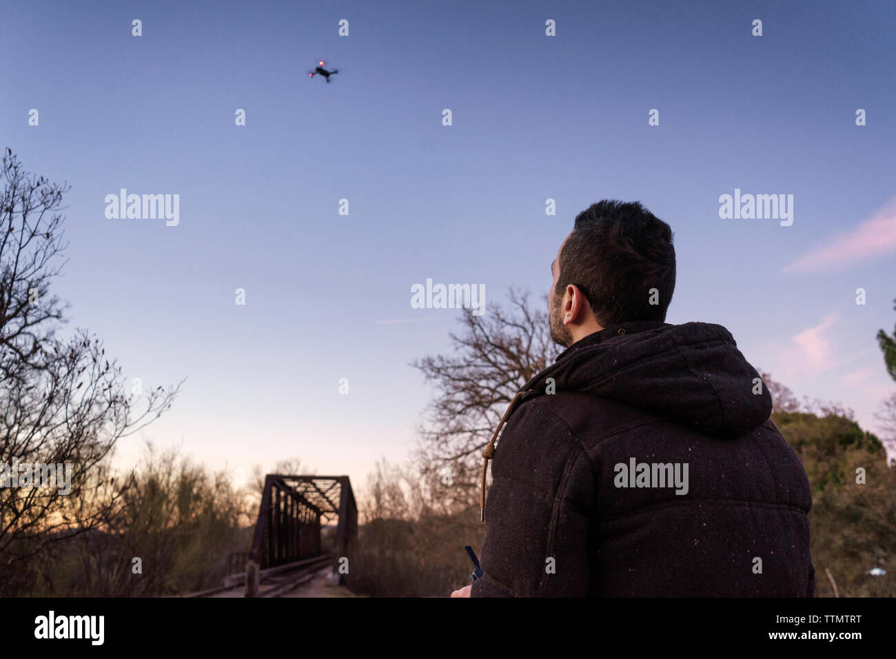 Man Flying drone against sky during sunset Stock Photo