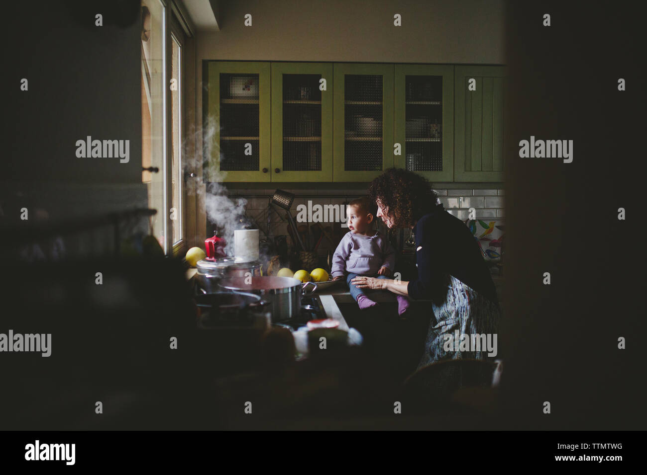 Young baby girl sitting on gramma's kitchen counter  looking outside Stock Photo