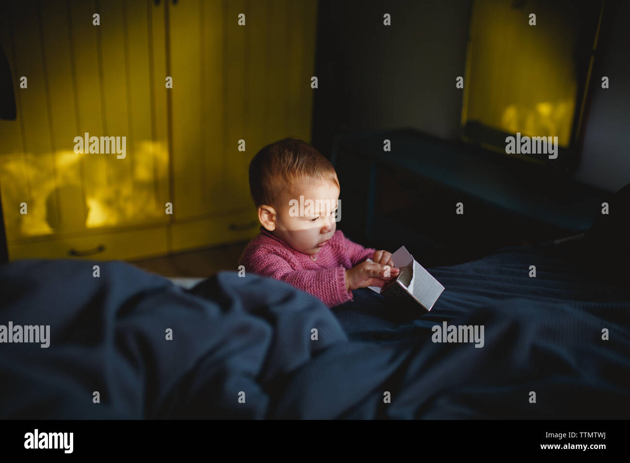 A baby girl playing with an empty carton box on bed Stock Photo