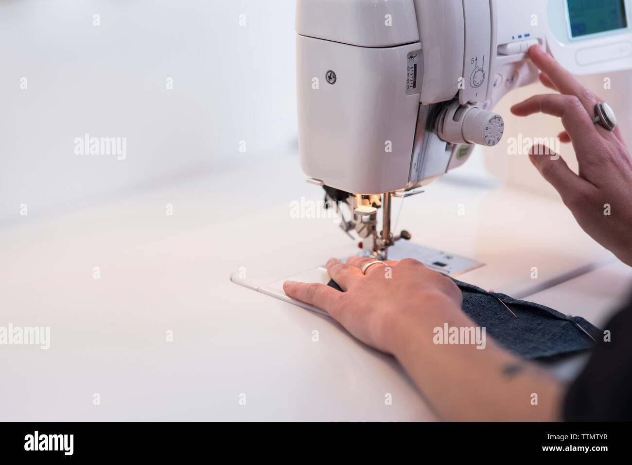 Cropped image of female tailor using sewing machine at table Stock Photo
