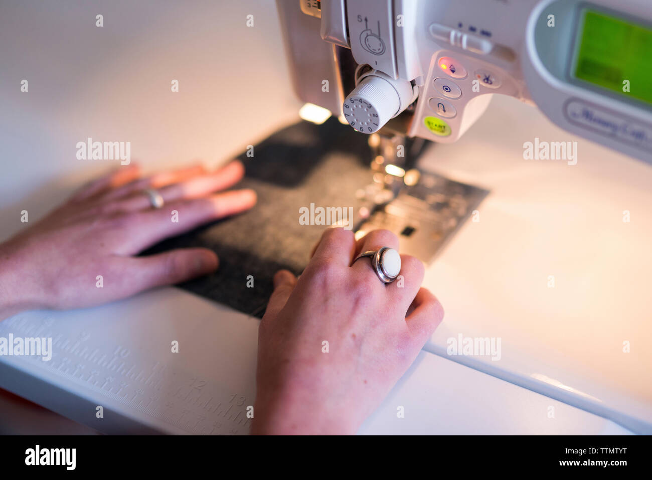 Cropped image of female tailor using sewing machine at table in workshop Stock Photo