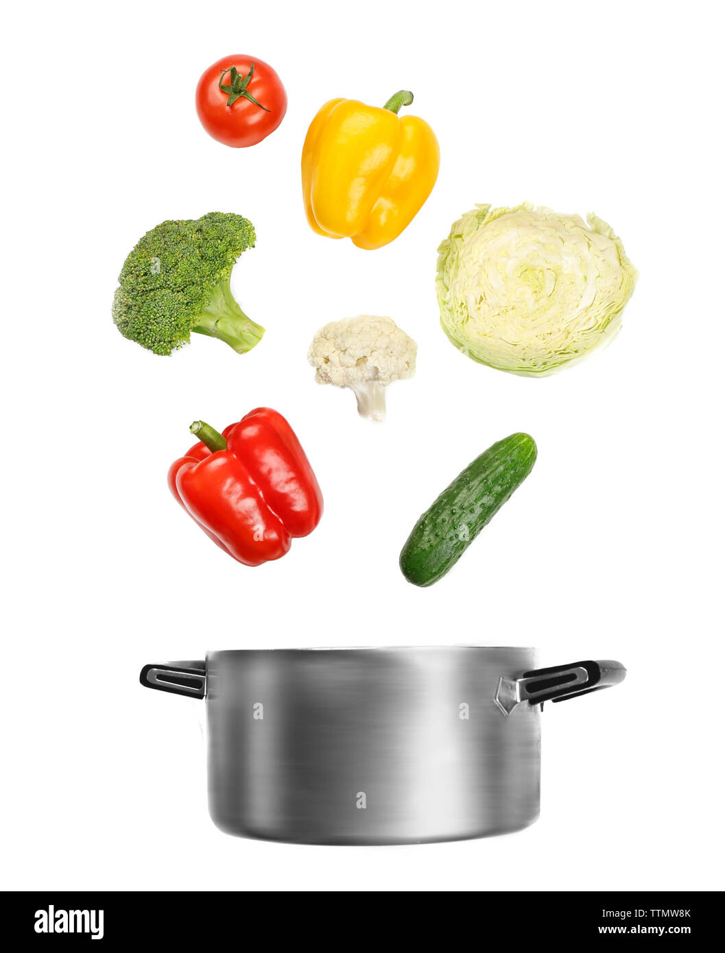 Fresh vegetables falling into a casserole pot on white background Stock Photo