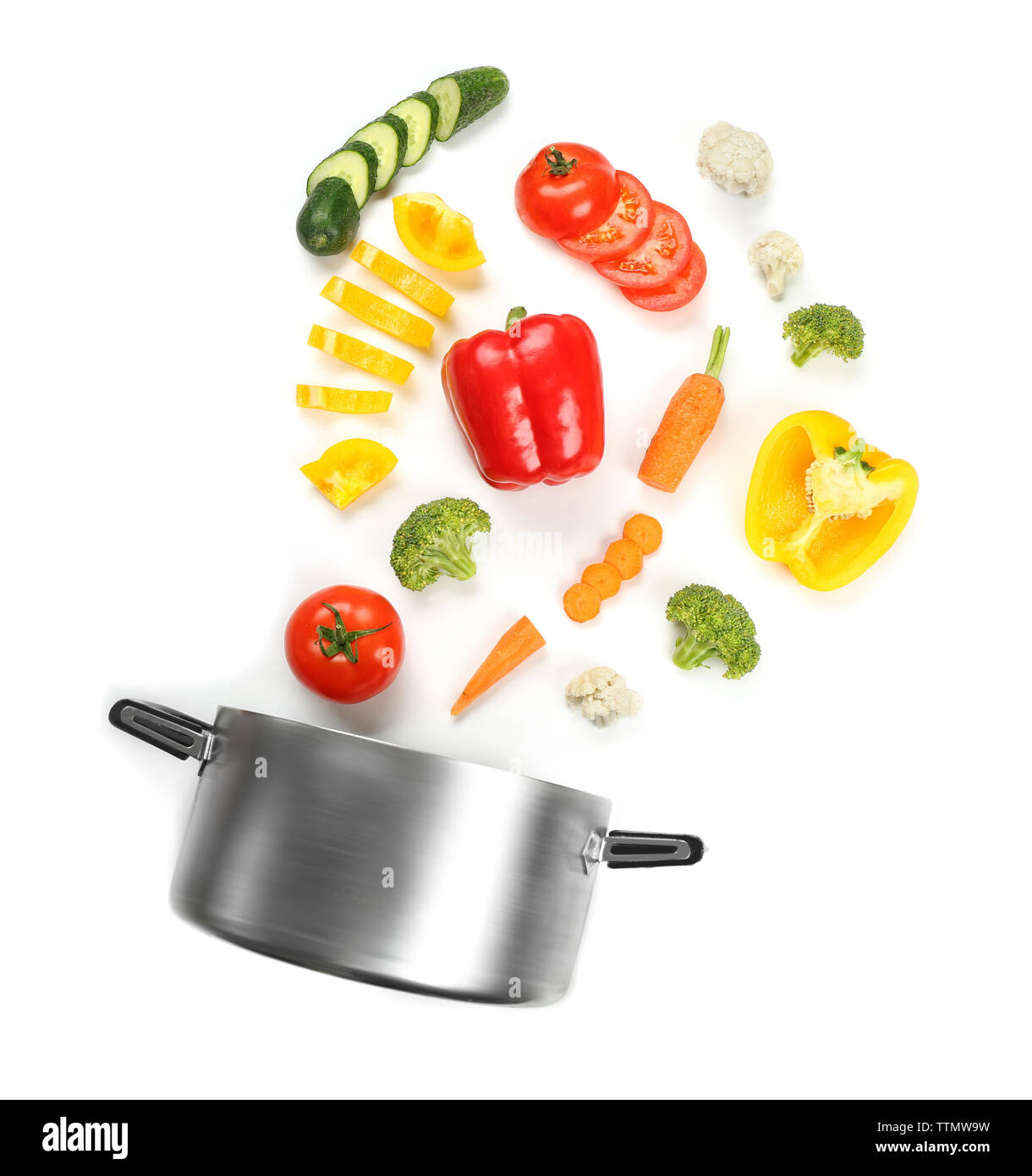 Fresh vegetables falling into a casserole pot on white background Stock Photo