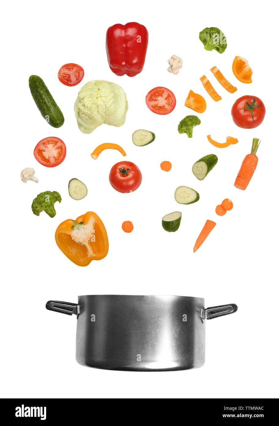 Different vegetables falling into saucepan on white background Stock Photo