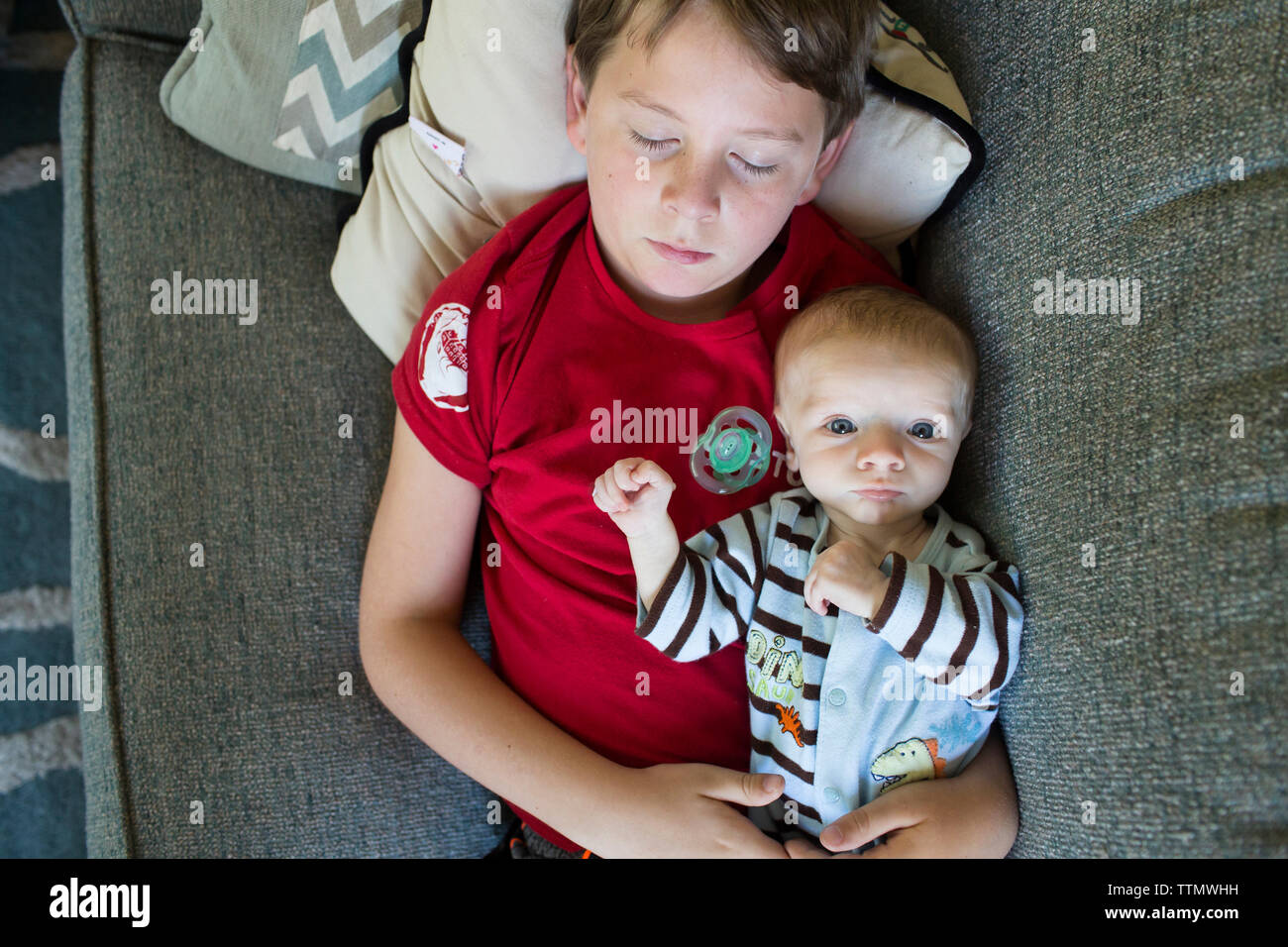 Overhead portrait of baby boy lying with sleeping brother on bed at