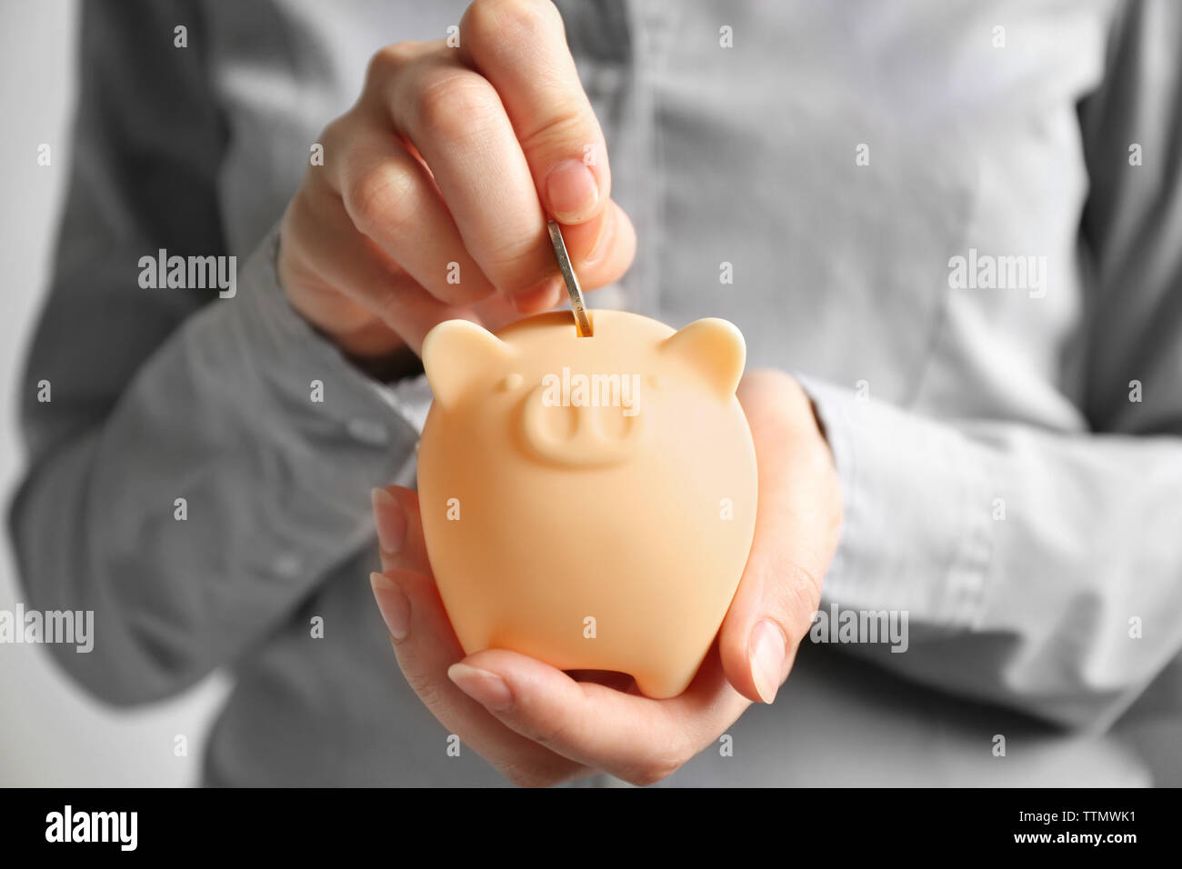Woman putting coin in piggy bank Stock Photo - Alamy