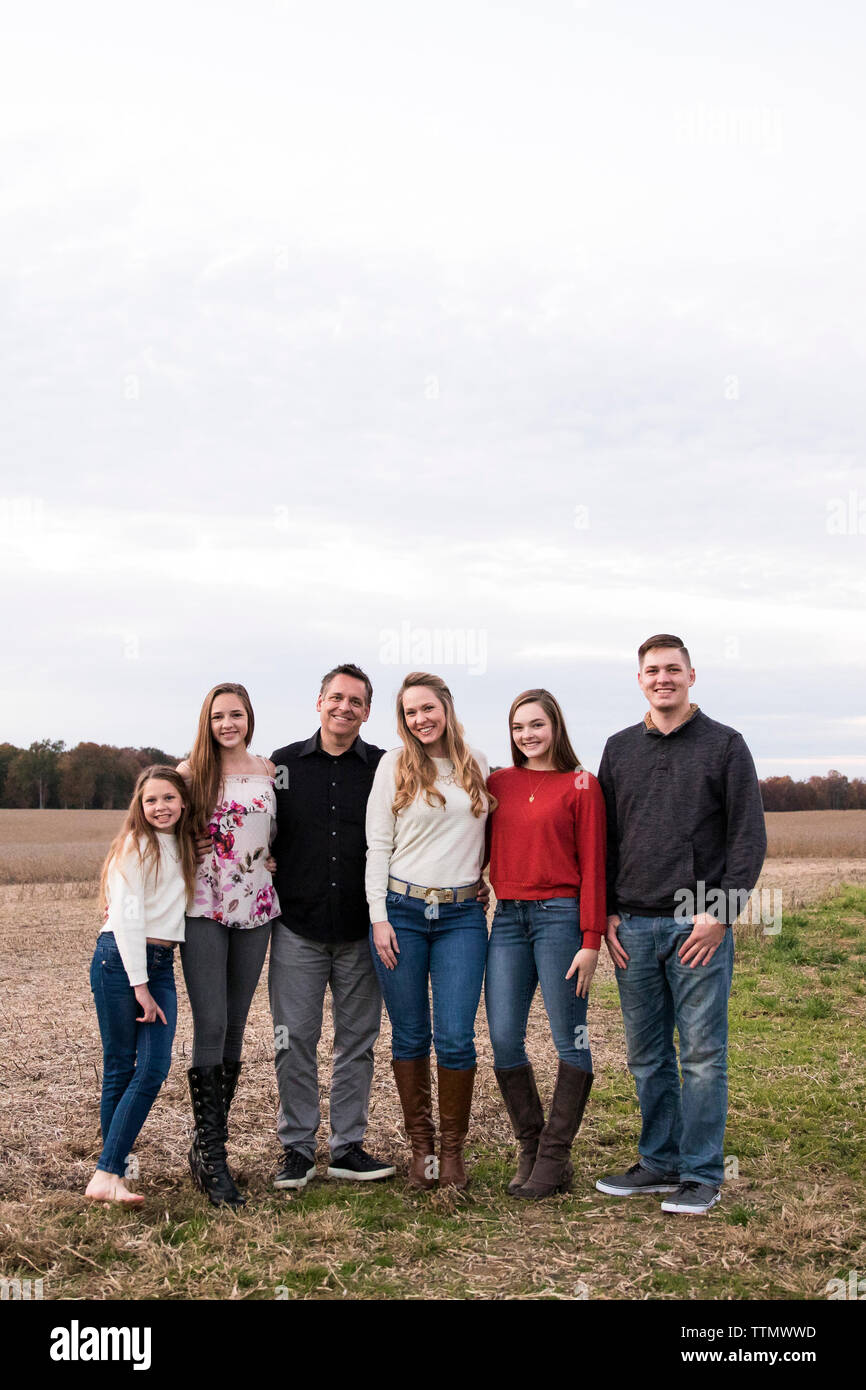 Large Family of Parents and Teenagers Stands in Farm Field At Sunset Stock Photo