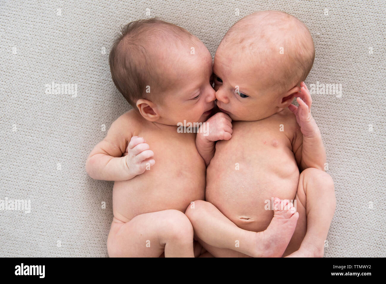 Newborn Twin Girls Laying Together on Off-White Blanket Stock Photo
