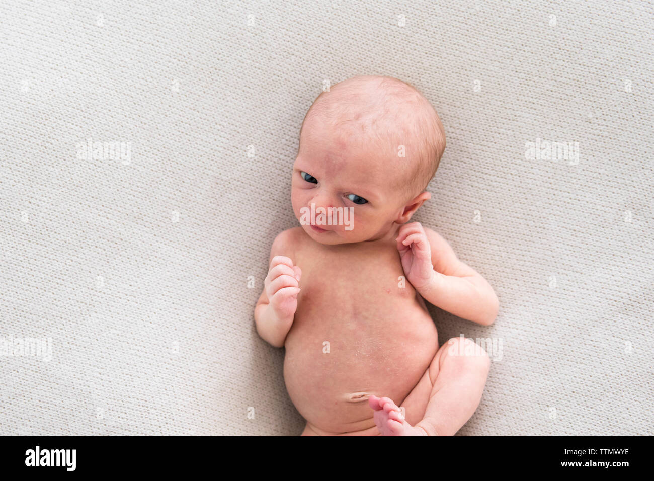 Overhead of Awake, Alert Newborn Baby Girl Laying on White Blanket Stock Photo