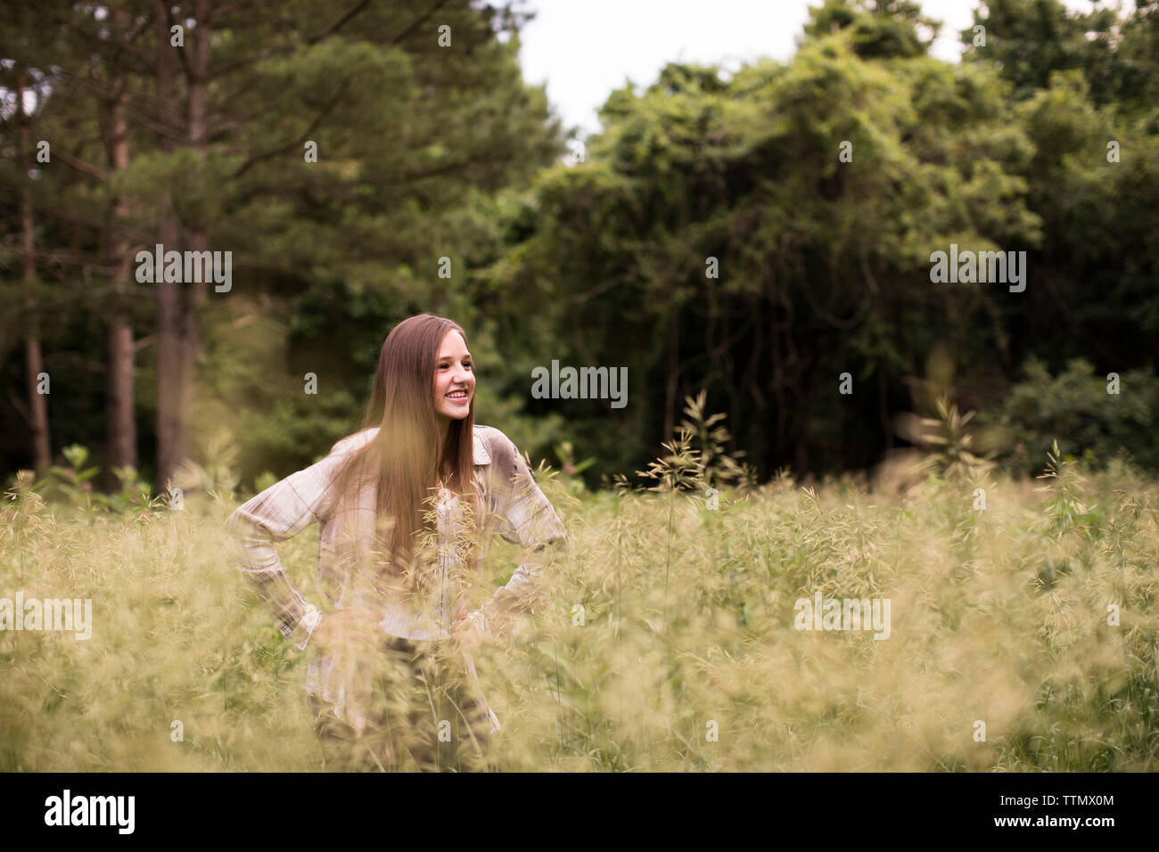 Smiling Teenage Girls Stands in Green Field in Front of Woods Stock Photo