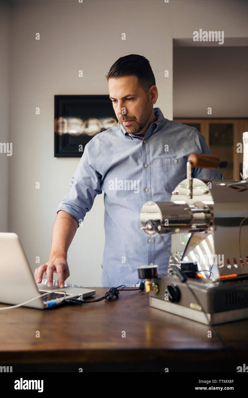 Man using laptop and coffee roaster in cafe Stock Photo