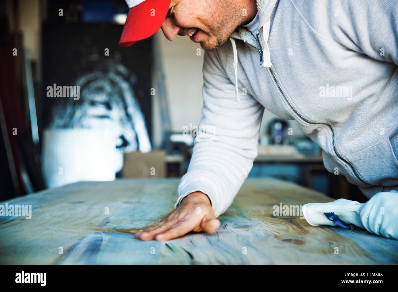Cropped image of smiling man touching wooden surface at workshop Stock Photo