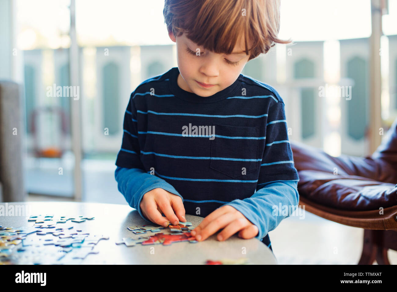 Boy solving jigsaw puzzle at home Stock Photo