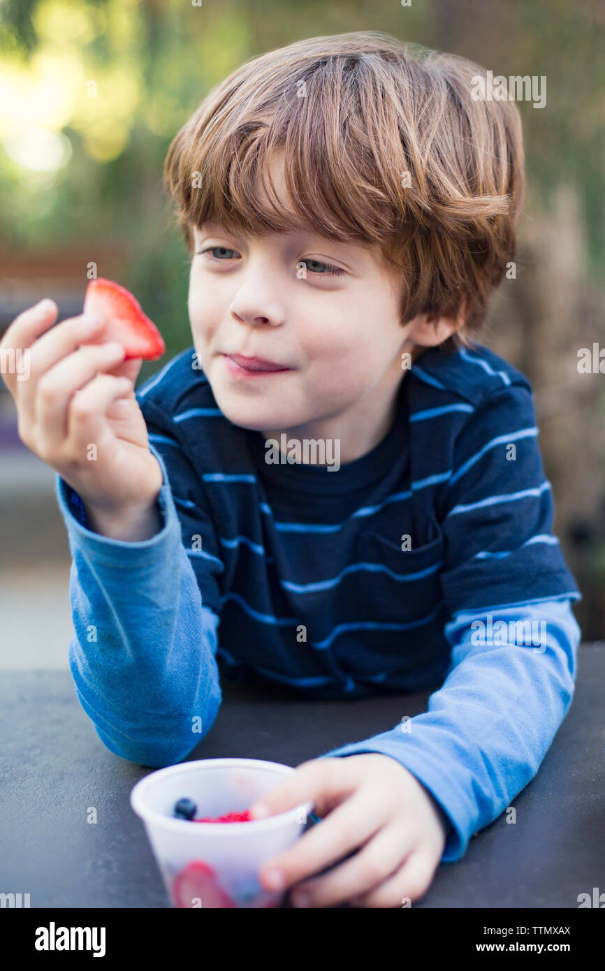 Smiling boy eating strawberry outdoors Stock Photo