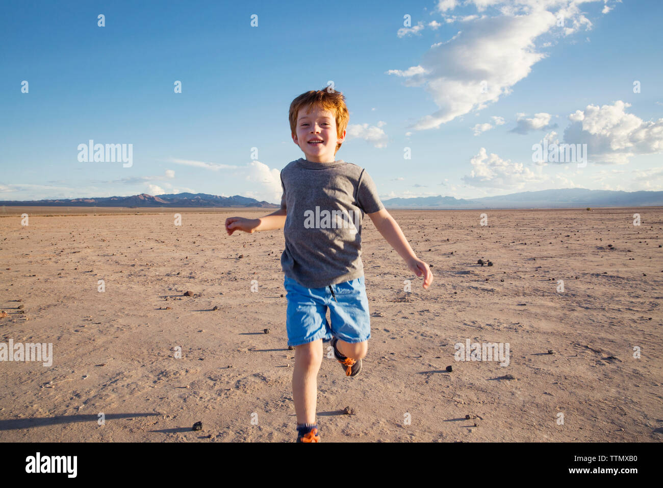 Portrait of happy boy running on arid landscape Stock Photo - Alamy